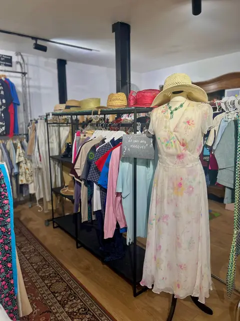 Le coin textile : portants de vêtements, chapeaux de paille et robe fleurie sur mannequin.