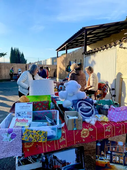 Des bénévoles de La Source derrière un stand chargé d'objets, un matin d'hiver.