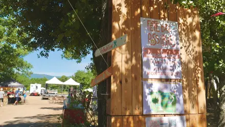 L'affiche de la Fête des Possibles 2026 clouée sur un panneau de bois, devant les barnums et la scène.