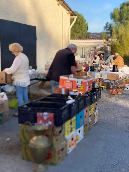 Des bénévoles installent les caisses et les tables du vide-grenier devant les locaux, au petit matin.